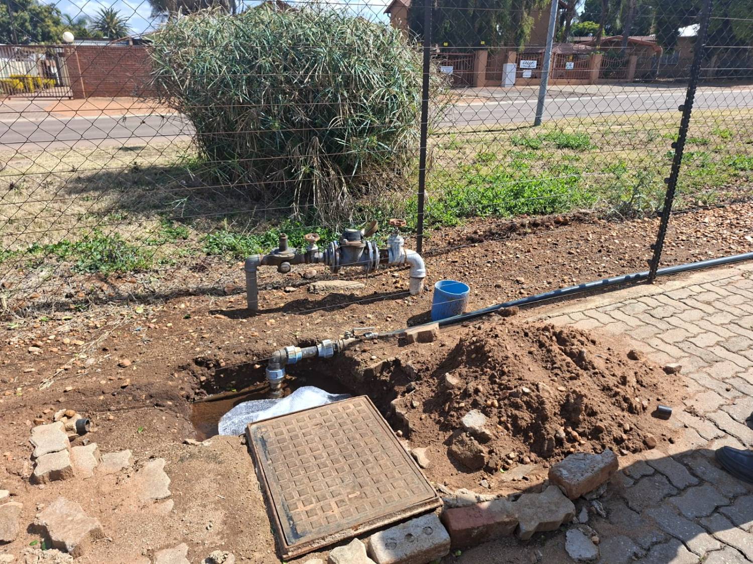 Water meter and valve assembly at a boundary fence with a new supply line being laid